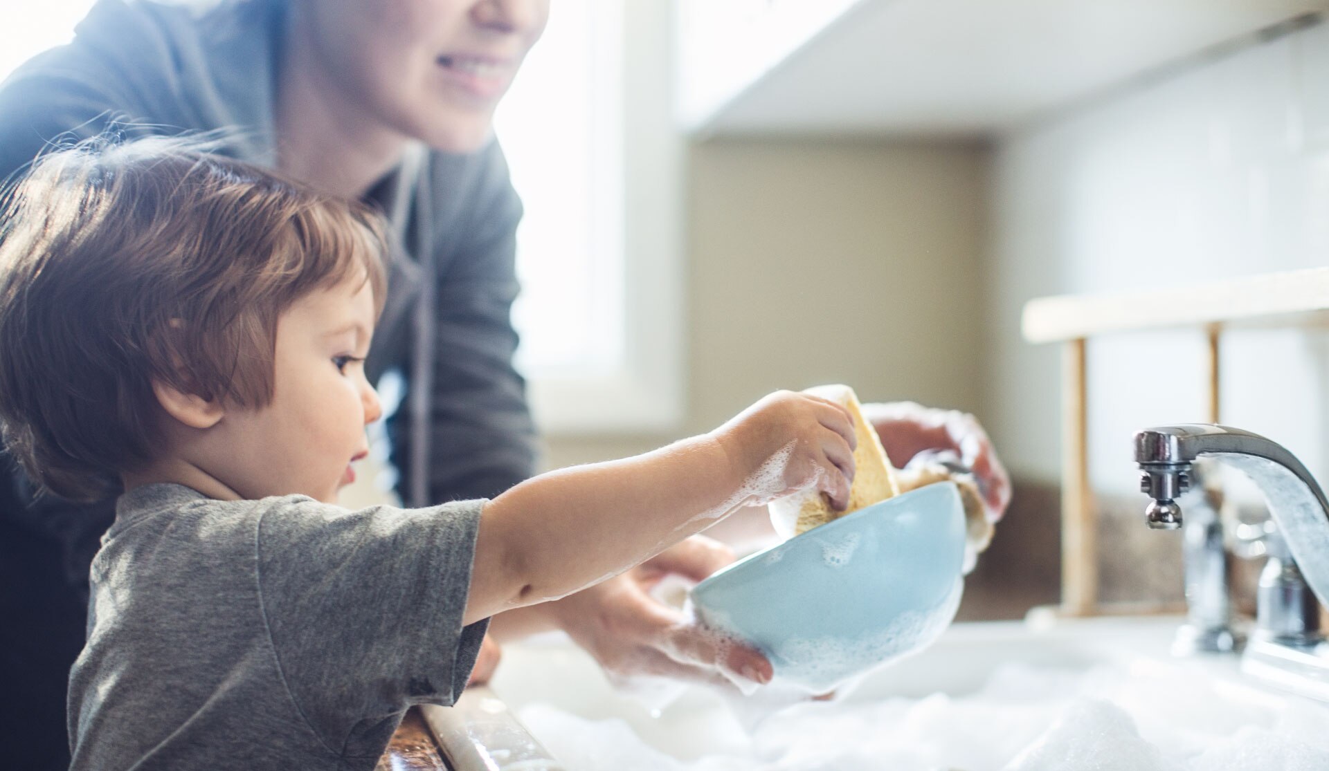 kid and woman washing the dishes in the kitchen